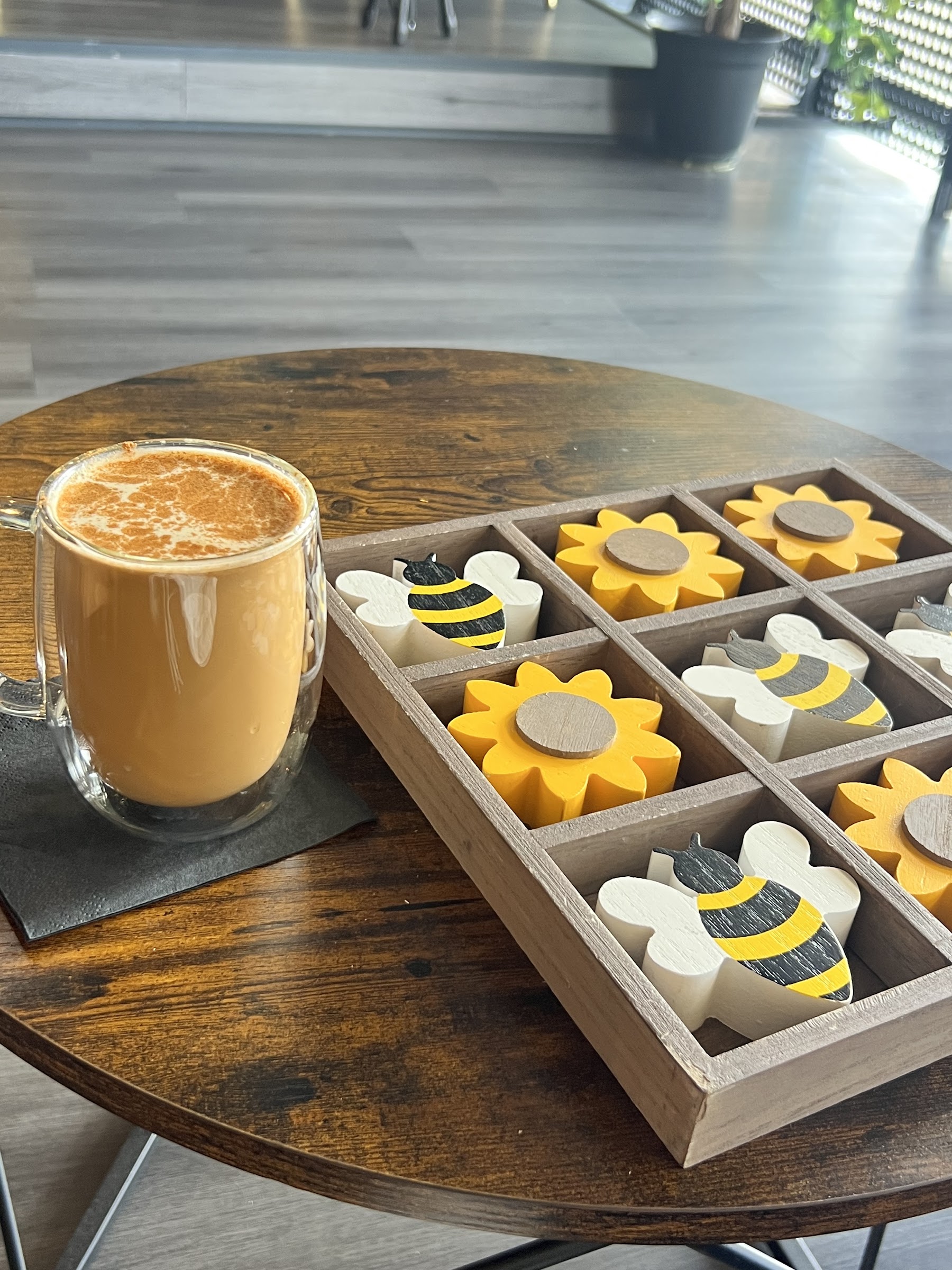 Carla's Coffeehouse latte beside a bee-themed tabletop game