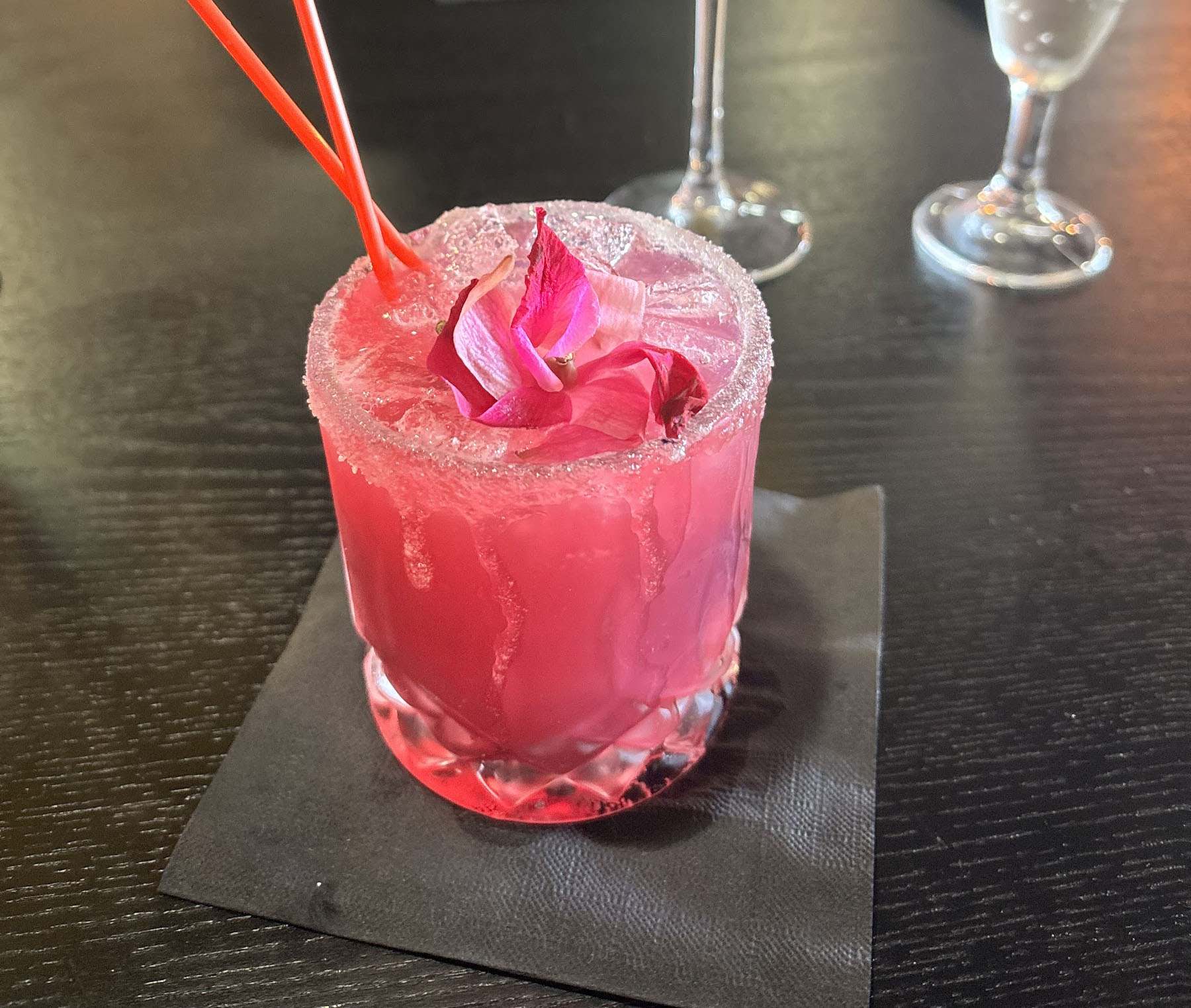 Bright pink mocktail with a sugared rim and flower garnish
