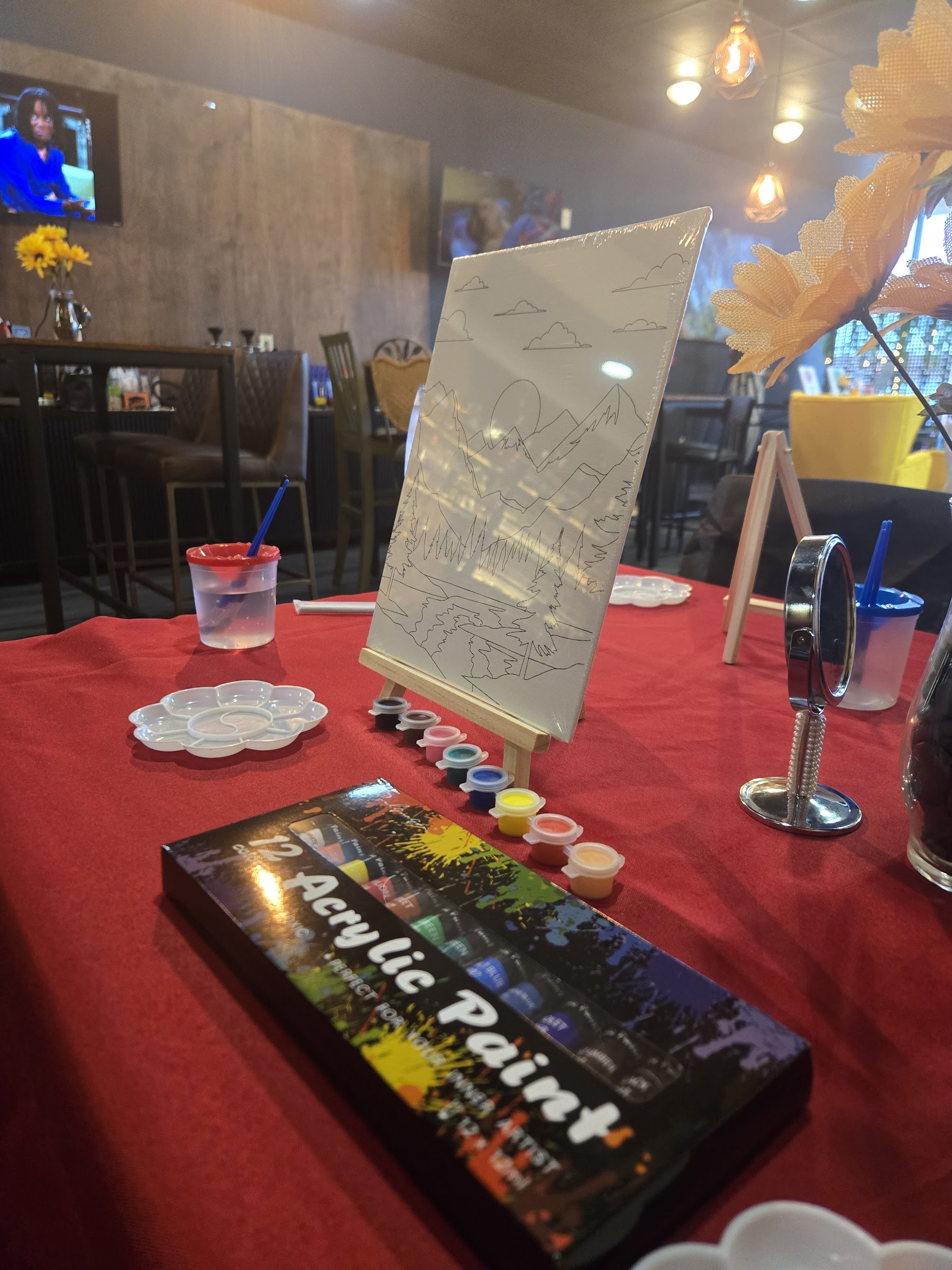 Paint-and-sip station with canvas, acrylic paints, and brushes