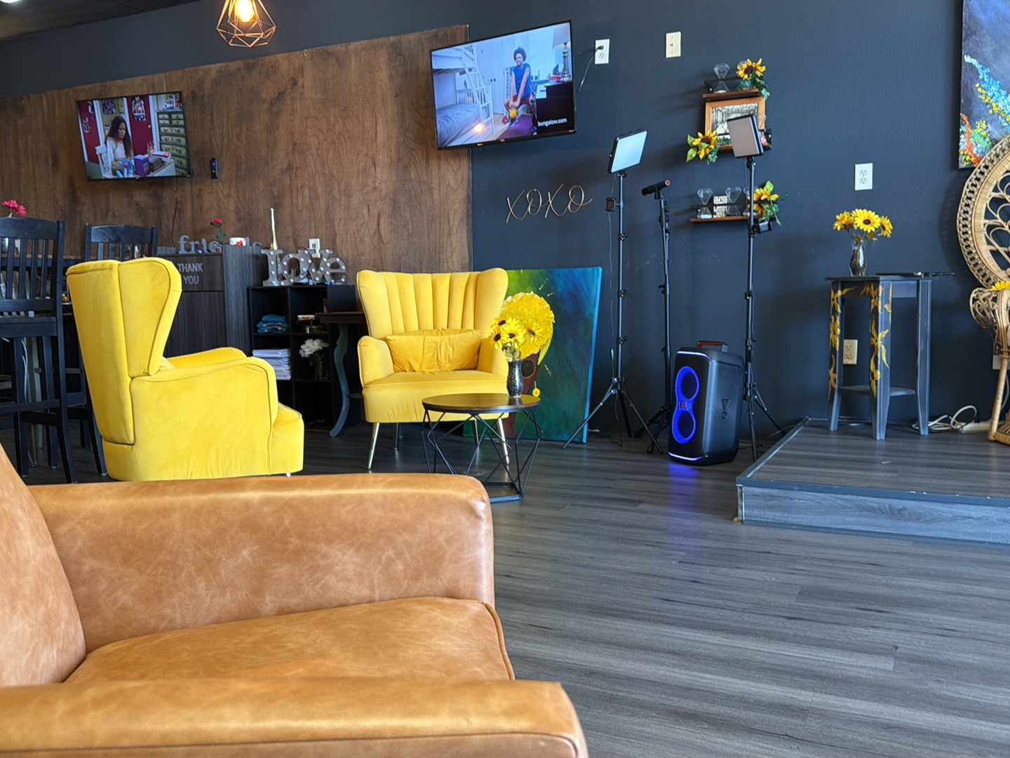 Lounge area with yellow velvet armchairs, sunflower decor, and a small stage.