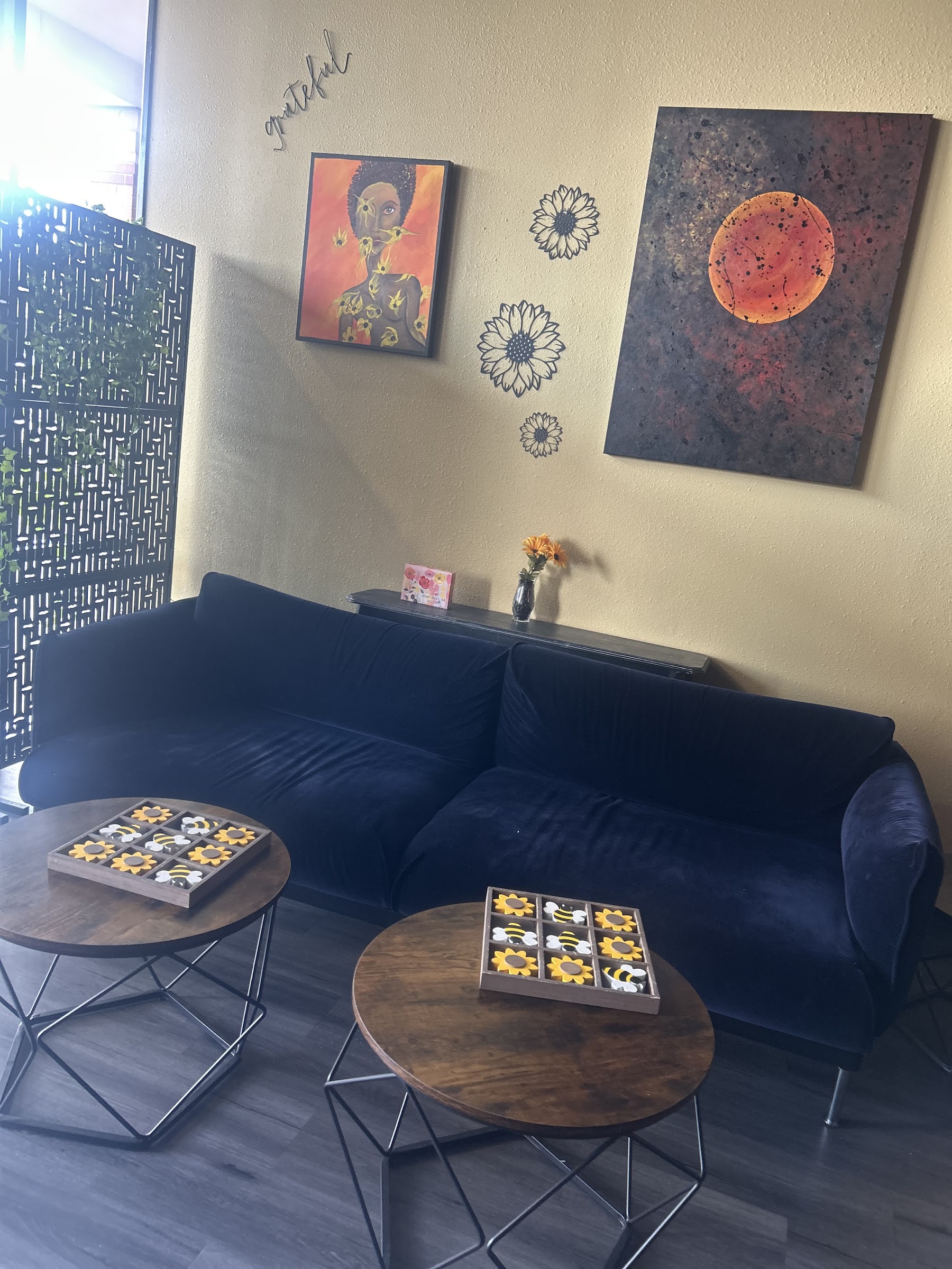 Blue velvet sofa seating area with sunflower and bee tic-tac-toe games.